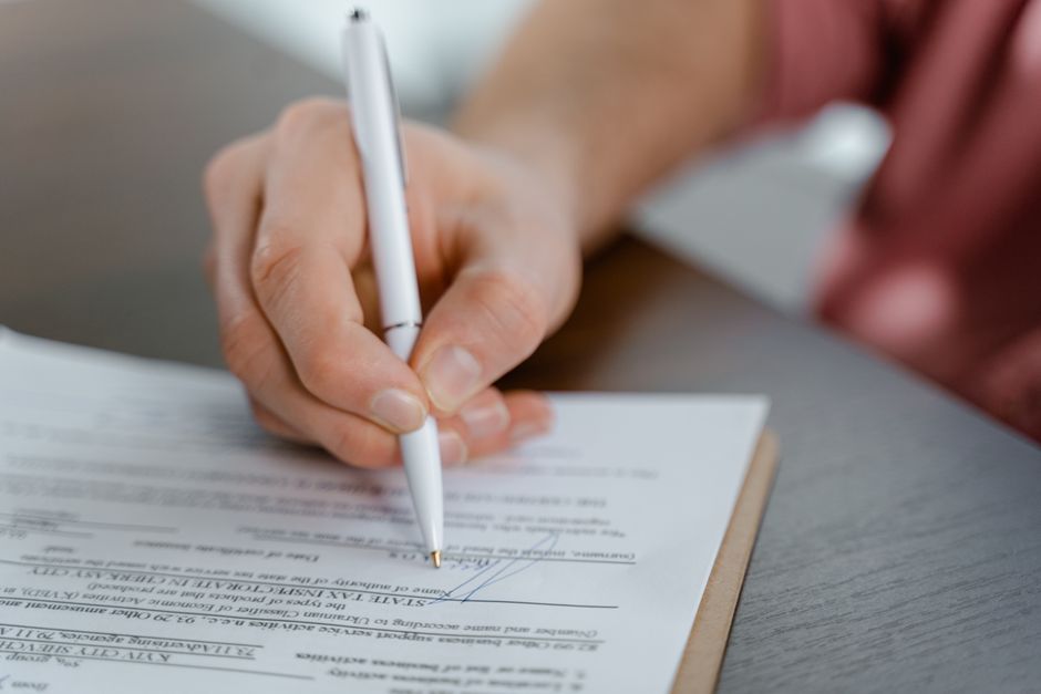 Close de mãos assinando documento de divórcio consensual em cartório de forma rápida.