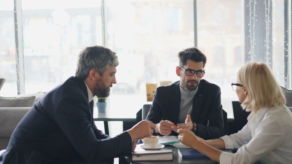 Mãe e pai conversando seriamente sobre responsabilidades financeiras em uma mesa de escritório