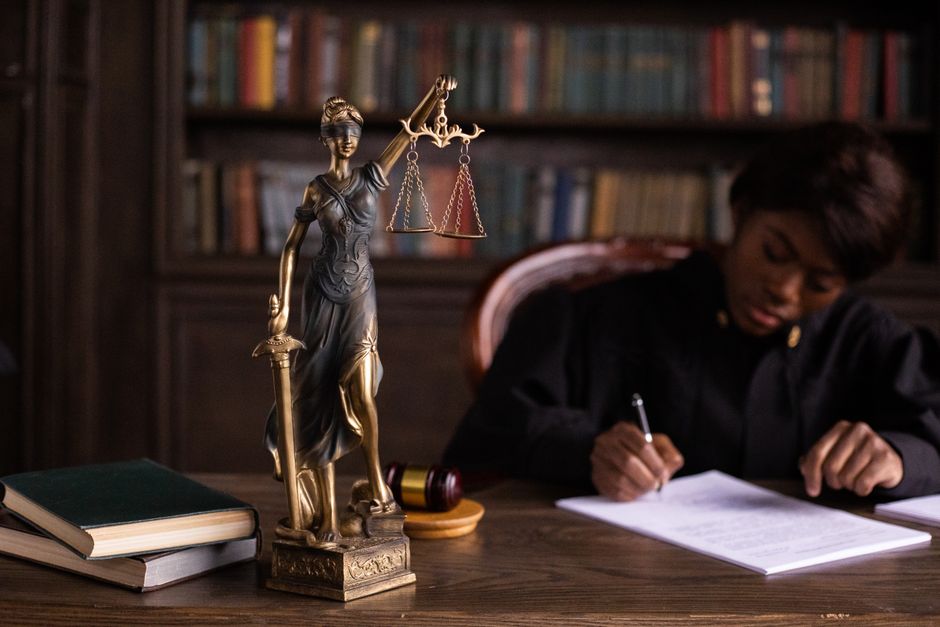 Ministro do tribunal assinando documentos oficiais em uma mesa de madeira